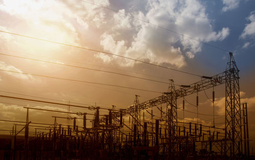 Low angle view of electricity pylon against cloudy sky