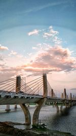 Low angle view of bridge over river against cloudy sky