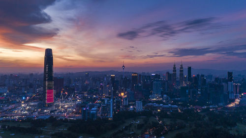 Illuminated cityscape against sky during sunset