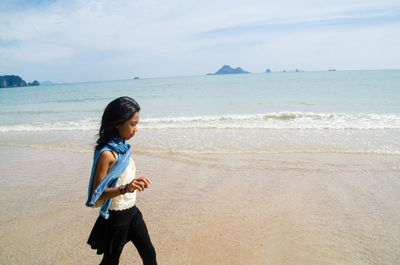 Full length of woman standing on beach against sky