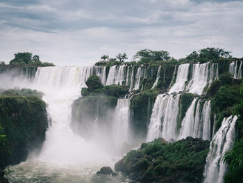 Scenic view of waterfall in forest against sky