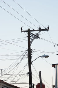 Low angle view of electricity pylon against clear sky