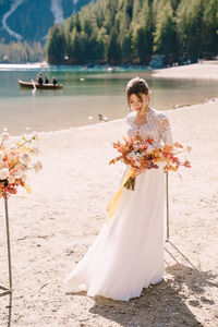 Bride holding bouquet looking away by riverbank