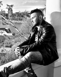 Young man looking away while sitting outdoors