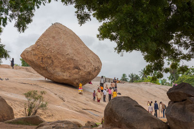 People on rock against sky