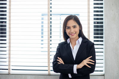 Portrait of smiling woman standing against window