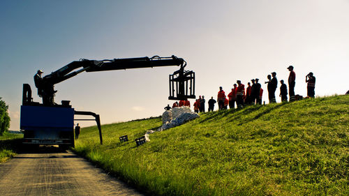 Machinery and workers against clear sky at construction site during sunset