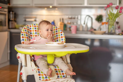 Cute girl sitting on table at home