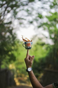 Close-up of hand holding tea cup on finger