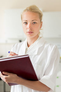 Portrait of beautiful woman writing in diary while standing in laboratory