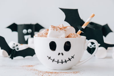 Painted white cup scary jacks face with marshmallows hot chocolate cacao drink diy for kids. 
