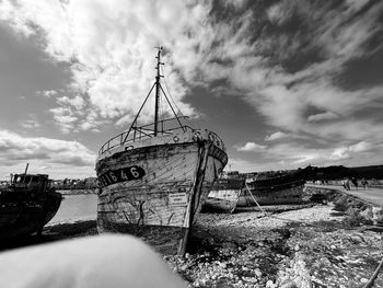 Old boat moored on beach against sky