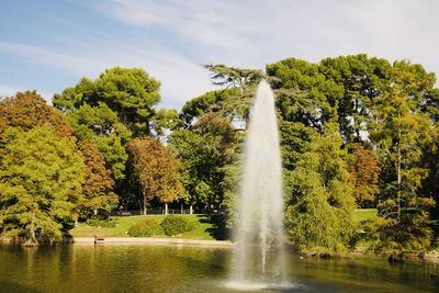 Fountain by lake against sky