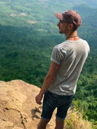 High angle view of hiker standing on cliff against landscape