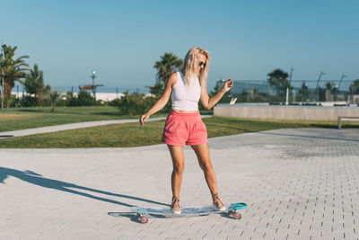 A beautiful skate woman rides her longboard.