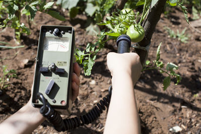 Close-up of woman holding geiger counter on agriculture field