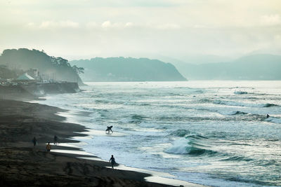 Scenic view of sea and silhouette people against sky