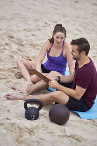 Full length of people talking over paper at beach