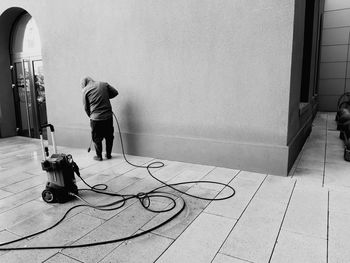 Rear view of man cleaning floor against wall