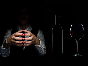 Midsection of man holding smart phone against black background