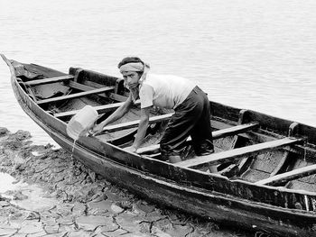 Man sitting on boat moored at sea shore