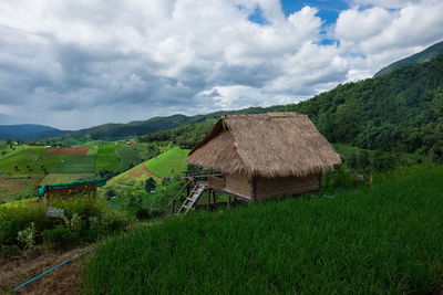 Scenic view of field by houses against sky