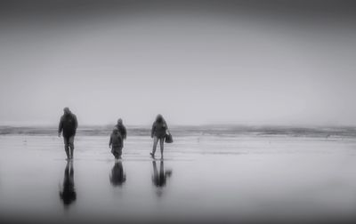 Rear view of people walking on beach
