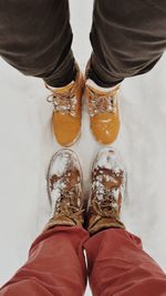 Low section of two people standing on snow face to face