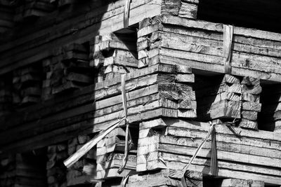 Low angle view of stack of logs against building