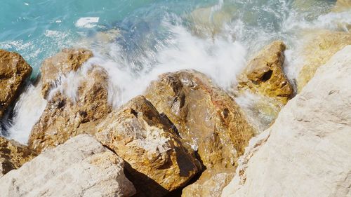 High angle view of rocks by sea during sunny day