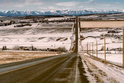 Road by snowcapped mountains against sky