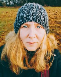 Portrait of woman wearing knit hat while standing on field