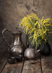 Close-up of yellow flowers in vase by cutlery on wooden table
