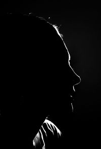 Close-up portrait of silhouette woman over black background