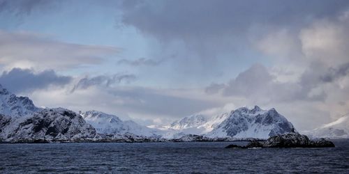 Scenic view of sea and snowcapped mountains against sky