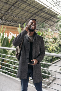 Close-up of smiling man talking on headphones while standing outdoors