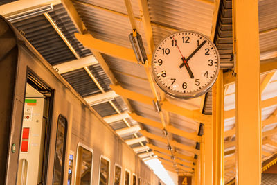 Low angle view of clock on wall in illuminated building