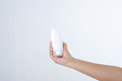 Close-up of hand holding glass over white background