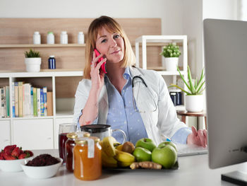 Portrait of young woman using mobile phone while sitting at home