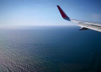 Close-up of airplane flying over sea against sky