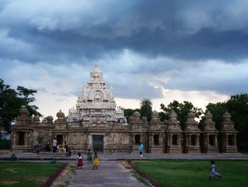 People in front of temple against cloudy sky
