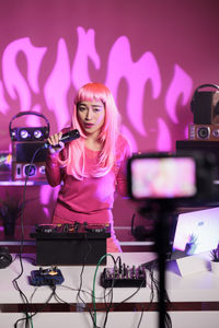 Portrait of young woman using mobile phone while sitting on stage