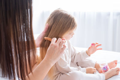 Mother combing hair of daughter