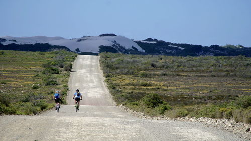 Rear view of people walking on road against mountain