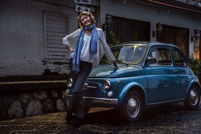 Portrait of young woman next to a vintage car