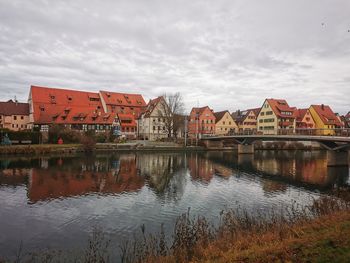 Buildings by river against sky in city