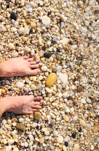 Close-up of feet on pebbles at beach