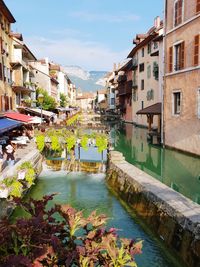 Canal amidst buildings in town against sky