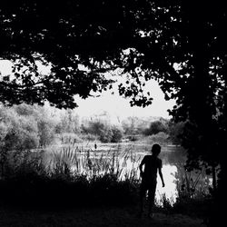 Silhouette of woman standing on lakeshore