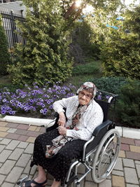 Senior woman sitting on wheelchair at yard